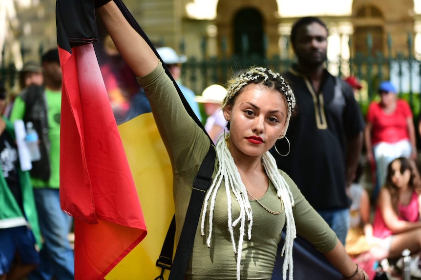 Joy Brimble holds up Australian Aboriginal flag outside Parliament House in Brisbane.