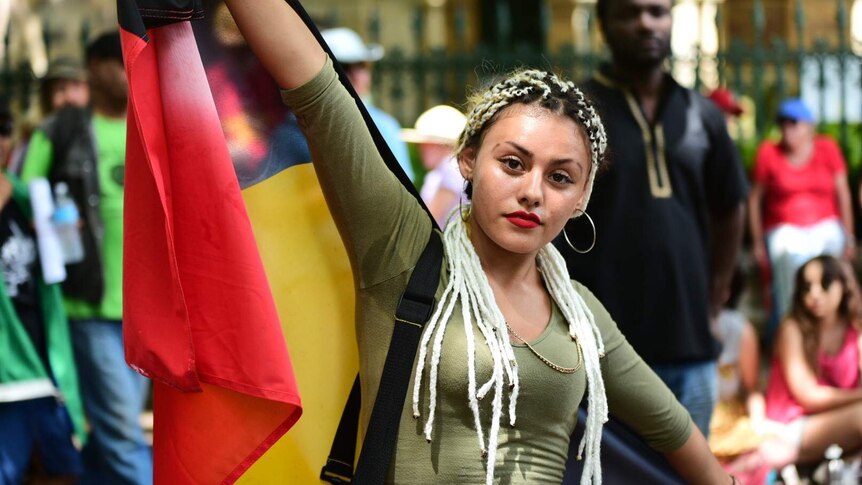 Joy Brimble holds up Australian Aboriginal flag outside Parliament House in Brisbane.