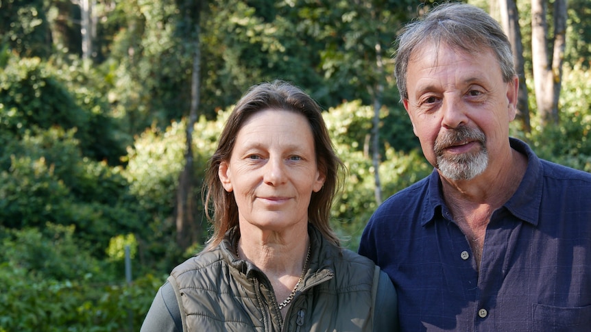 Janne and David Flinter next to each other with a lush green rainforest behind them.