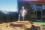 David Fahey stands at the site of the former kurrajong tree, with one boot raised on the stump.