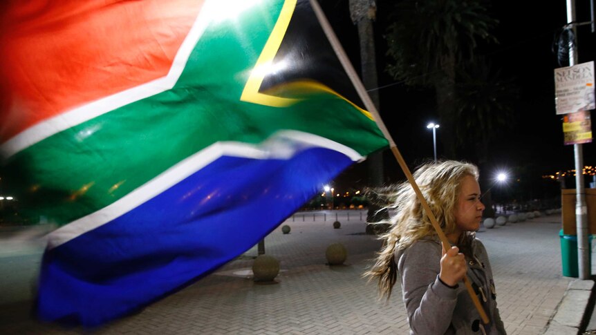 A girl holds a South African national flag