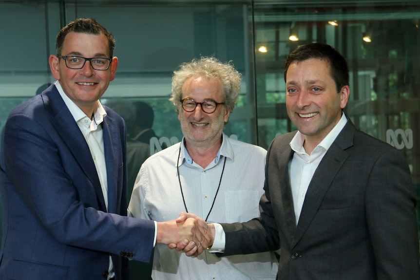 Daniel Andrews, Matthew Guy shake hands on front of Jon Faine.