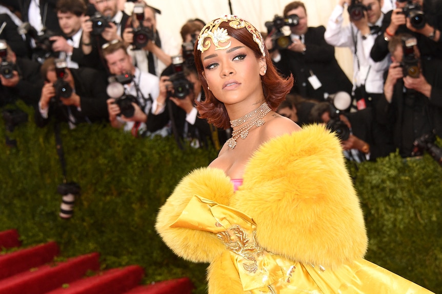 Rihanna in a yellow dress, her hair crowned with jewels