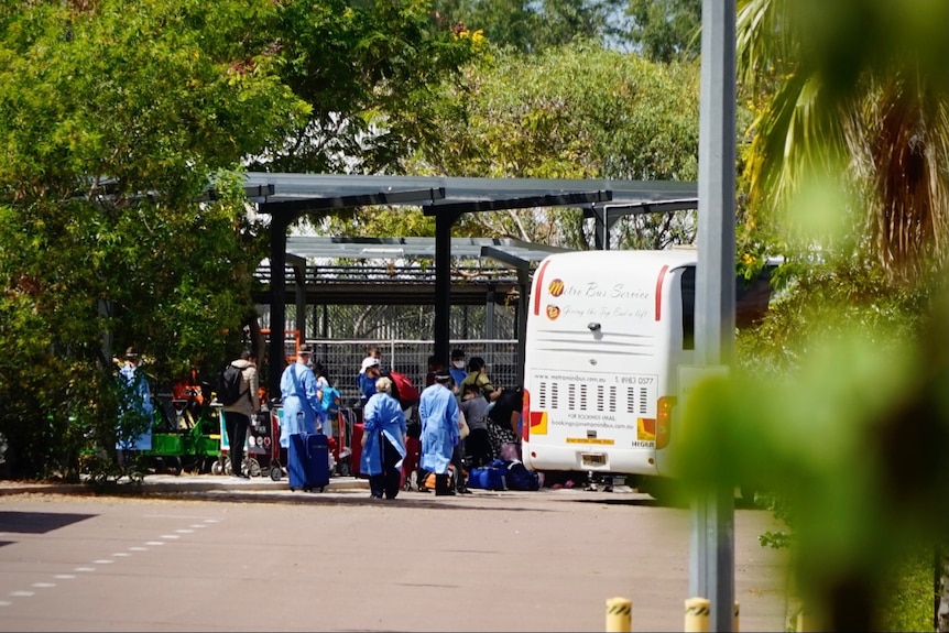 Passengers line up to board a bus at an airport