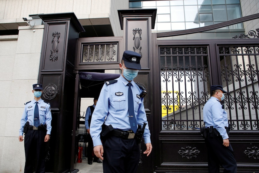 Three Chinese police officers outside a court building. 