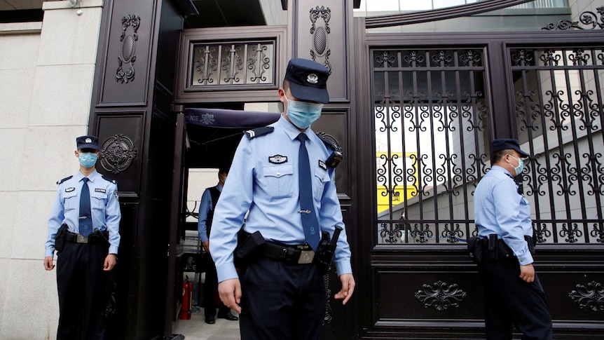 Three Chinese police officers outside a court building. 