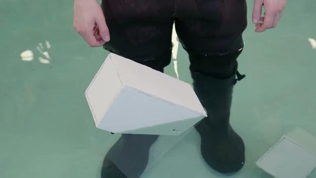 Legs of man standing in water, white block floats on its side