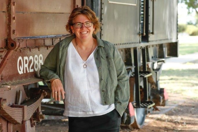 A woman standing in front of a train.