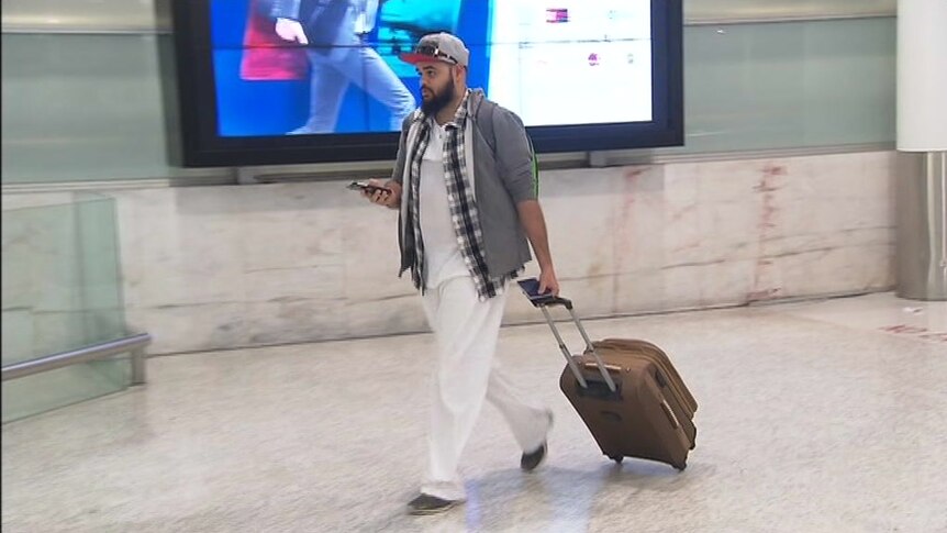 Zaky Mallah dragging his suitcase at the airport.