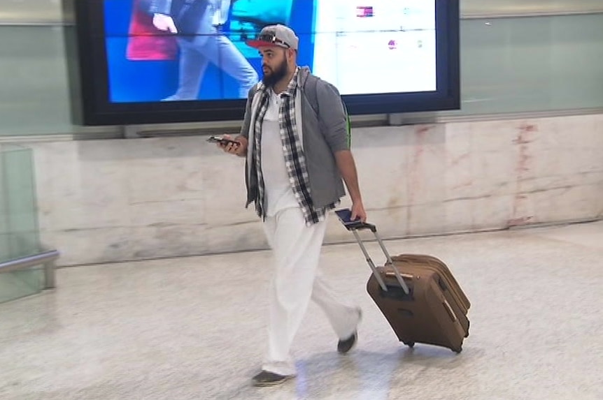 Zaky Mallah dragging his suitcase at the airport.