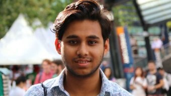 A young man of South Asian background smiles at the camera