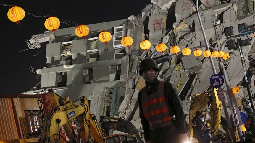 Soldiers stand guard in front of the collapsed building.