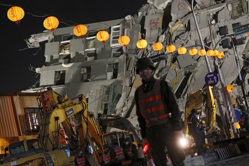 Soldiers stand guard in front of the collapsed building.