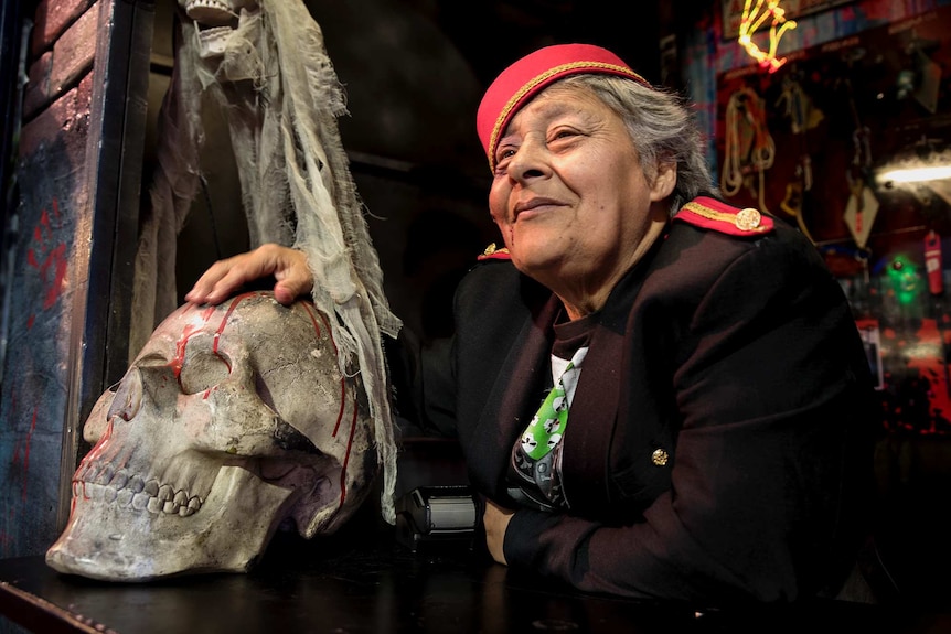 A ticket collector rubs a fake human skull inside a booth.