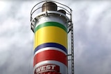 A chimney with green yellow blue white and red paint stripes on it.