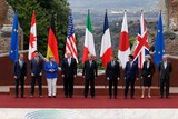 G7 leaders pose in a line in front of their respective flags in Sicily, Italy.