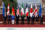 G7 leaders pose in a line in front of their respective flags in Sicily, Italy.