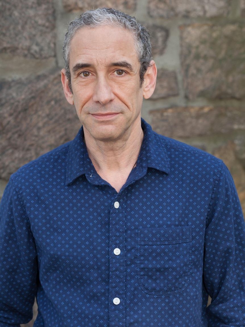 A middle-aged man with grey hair and a blue shirt.