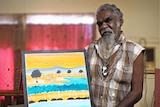 Indigenous man holds a bright artwork