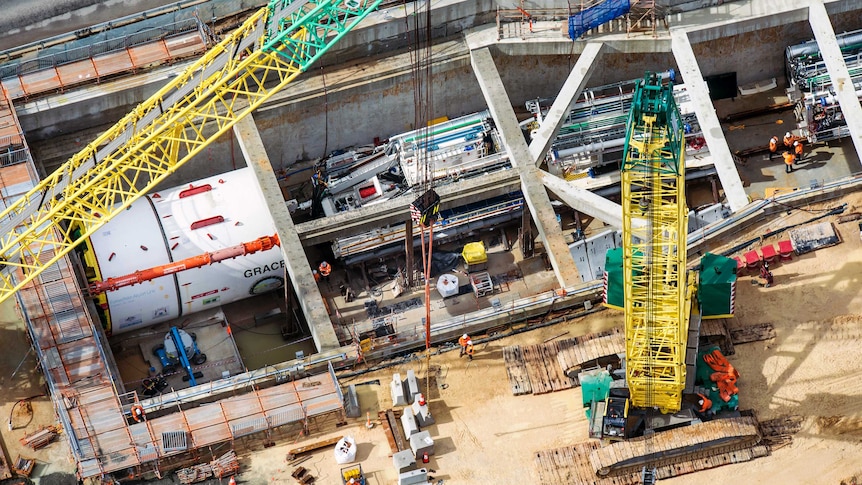 The tunnel boring machine in place, surrounded by concrete housing, workers and other equipment.