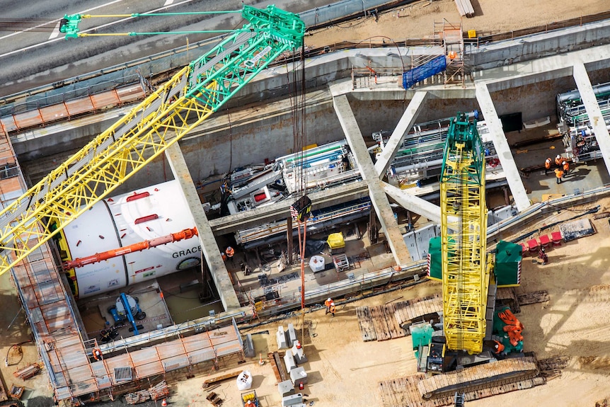 The tunnel-boring machine in place, surrounded by concrete housing, workers and other equipment.