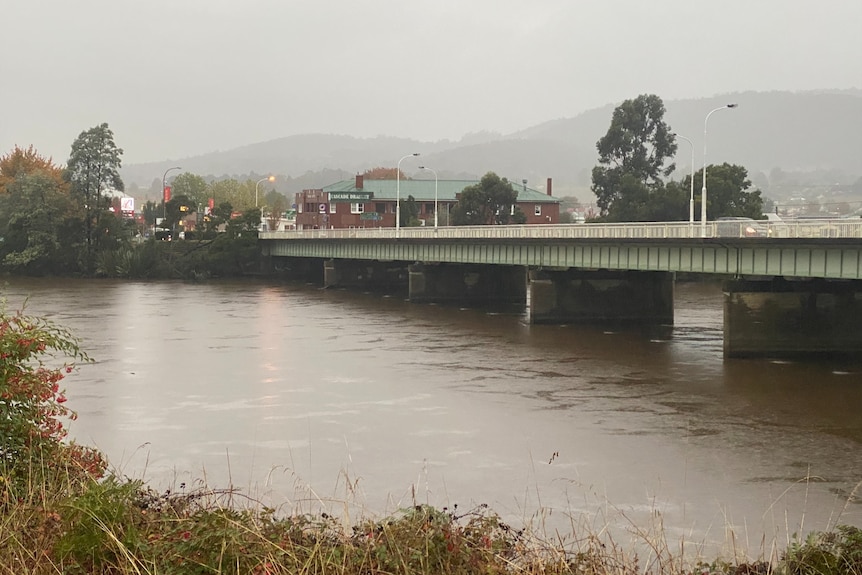 Muddy water flows under the Huon bridge at Huonville.