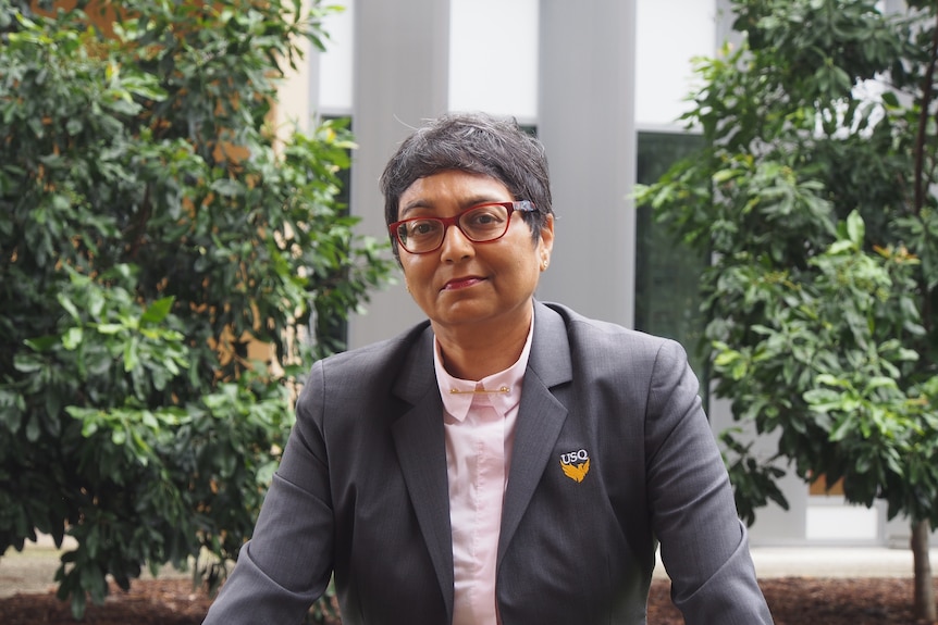 A woman in glasses stands outside.