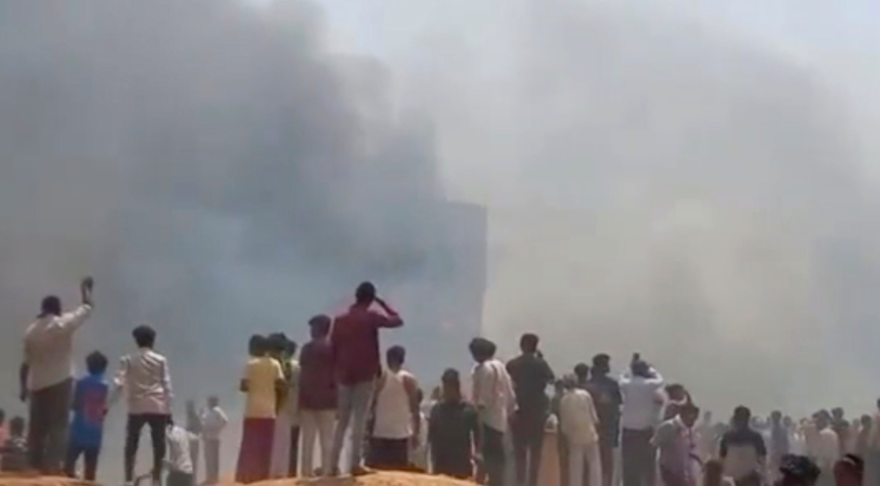 People watch smoke rising after an airplane crashed in Ahmedabad