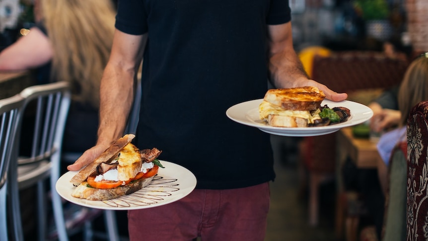 Waiter carrying breakfast orders with a plate in each hand