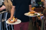 Waiter carrying breakfast orders with a plate in each hand