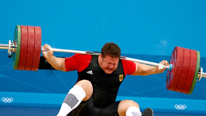 Matthias Steiner is struck by his falling weight after he dropped it during the +105kg snatch.