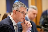 Rob Stefanic holds his hands together while giving evidence at senate estimates