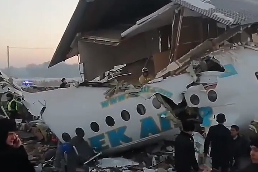 The wreckage of a Bek Air plane that crashed near Almaty airport. Part of the fuselage is stuck inside a building.