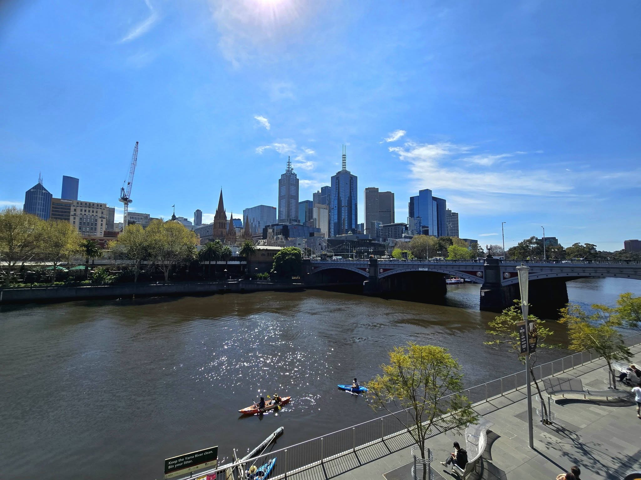 people inn boats on the yarra river in mebourne victoria as the sun shines over head