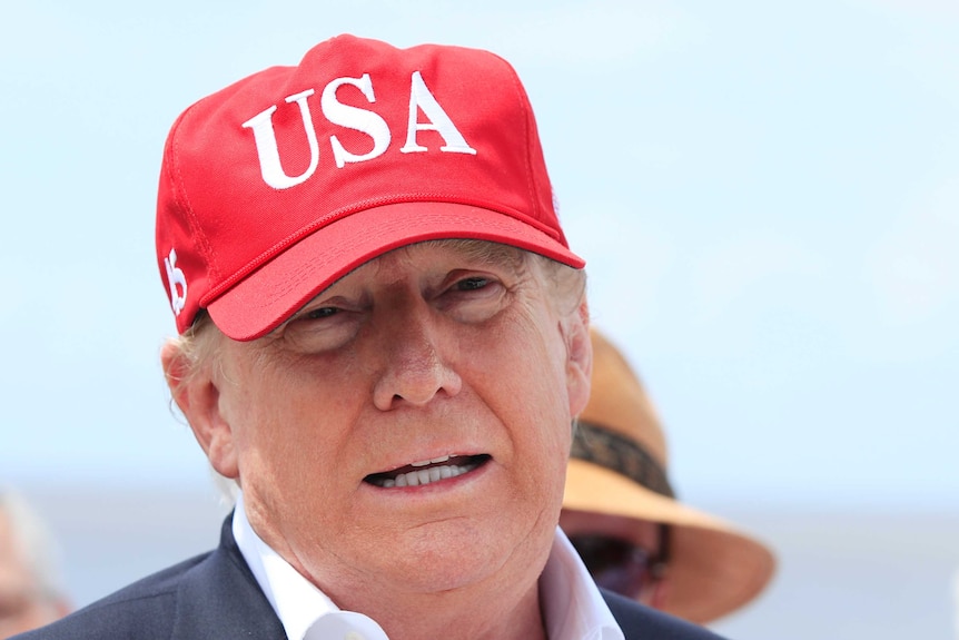 Close up shot of Donald Trump's face wearing a red hat with USA written on it