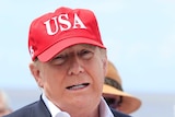 Close up shot of Donald Trump's face wearing a red hat with USA written on it