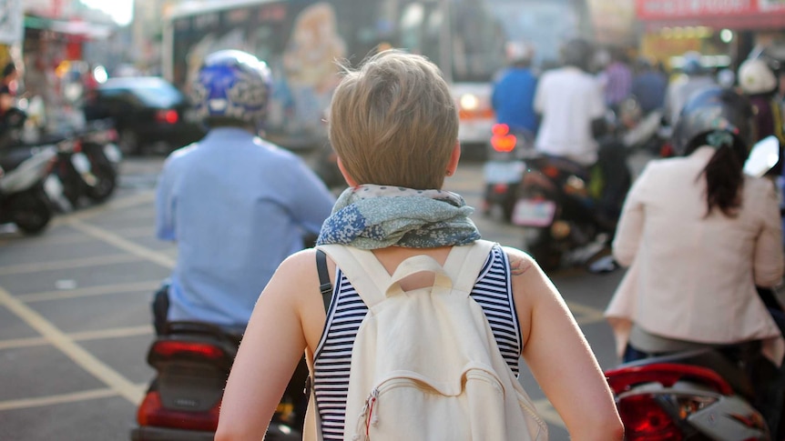 A woman travelling on her own navigates a busy street.