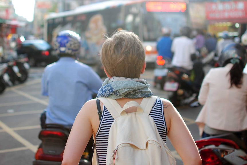 A woman travelling on her own navigates a busy street.