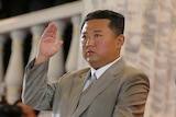 Kim Jong Un stares at something outside the frame, with his hand raised in a salute. 