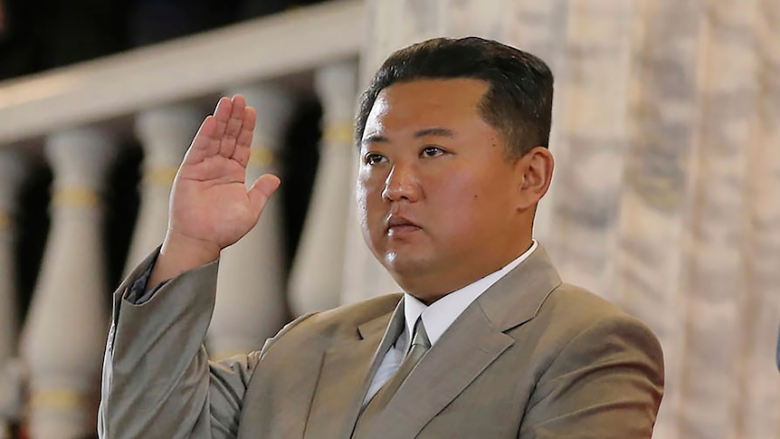 Kim Jong Un stares at something outside the frame, with his hand raised in a salute. 