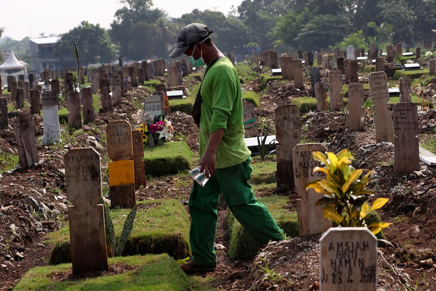 Seorang pekerja berjalan melalui pemakaman di Jakarta di kuburan korban COVID-19