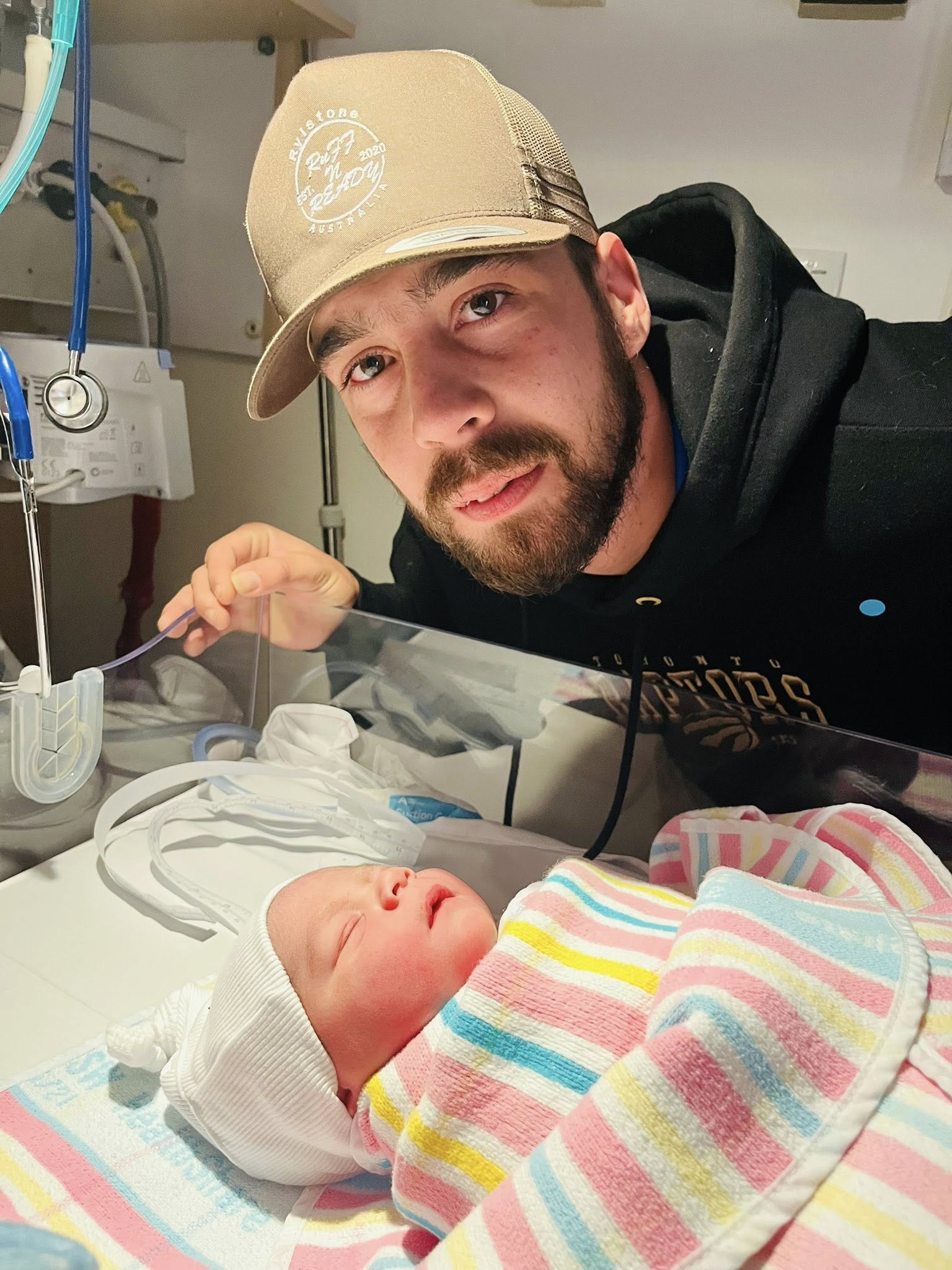 Un hombre se encuentra junto a un bebé recién nacido en una cuna.