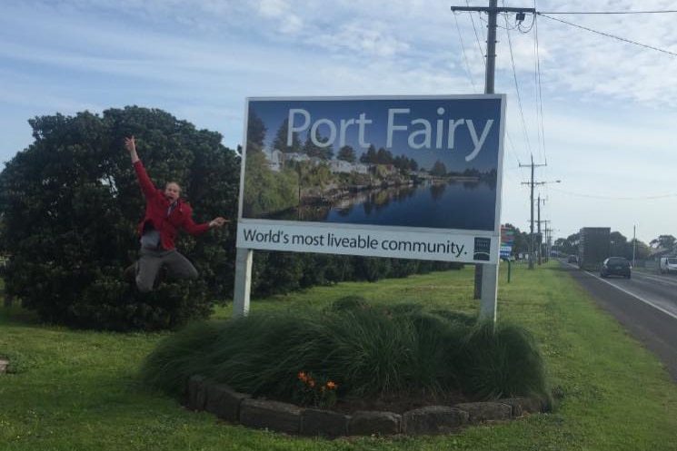 A man jumping next to a sign reading 'Port Fairy'