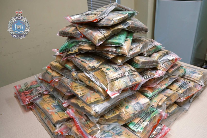 A large tower of cash in sealed plastic ziplock bags.