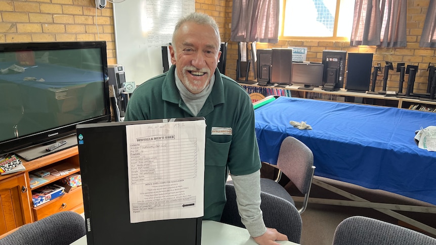 a male volunteer smiling next to a computer. 