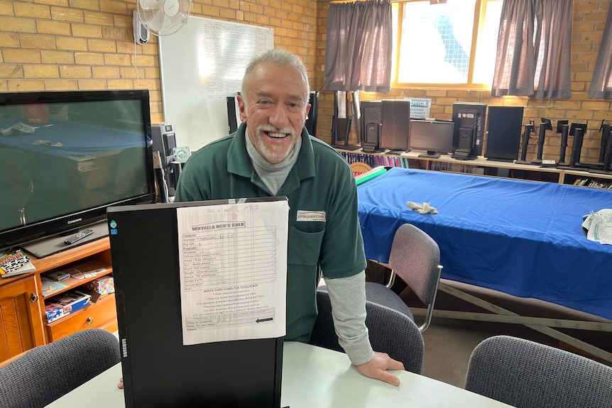 Whyalla Mens Shed volunteer smiling next to a computer. 
