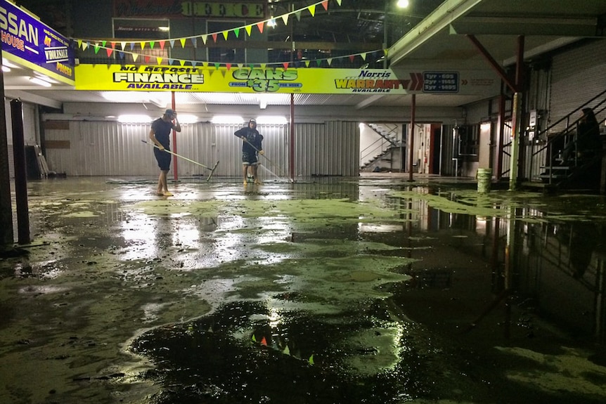 The clean up begins at a car dealership in Windsor, Brisbane after cars were filled with mud and debris.