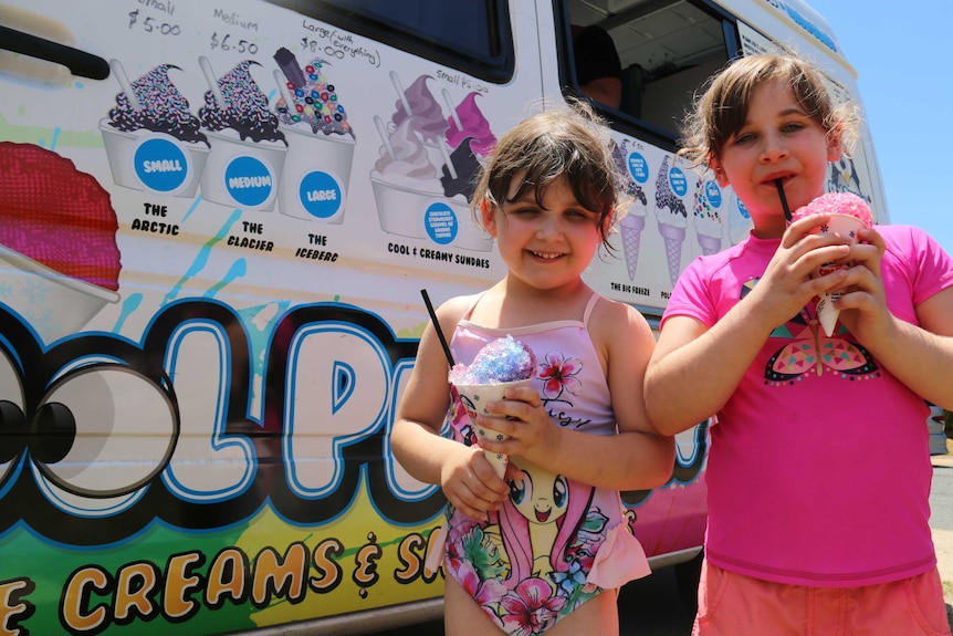 Two girls eating slurpies in front of ice-cream truck