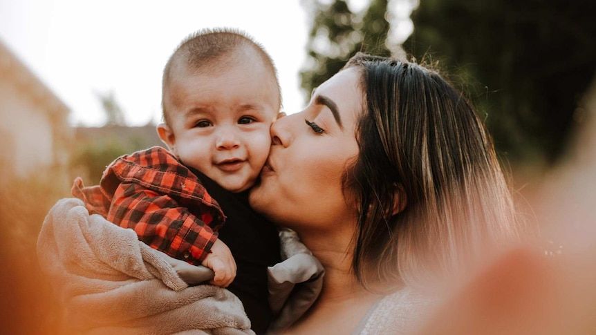 Woman kissing her baby son on the cheek to depict work rights information after returning from maternity leave.