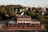 White birds fly over an old 1800s hotel 